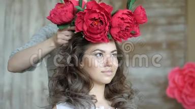 化妆师和模特一起工作。 一位造型师在女孩的模特头上戴`一个红色狮子圈。